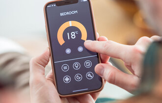Man using mobile phone to control termostat at home