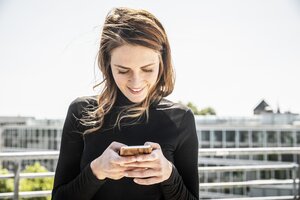 Smiling woman text messaging on roof terrace Smiling woman text messaging on roof terrace