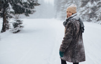 Eine Frau macht im schneebedeckten Wald einen Spaziergang.