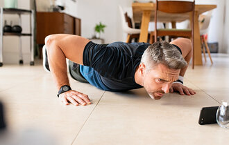 Mature,Man,Practicing,Pushups,Exercise,While,Watching,Video,On,Smartphone