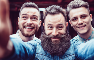 Drei Männer mit Bart und Schnauz die freudig in die Kamera schauen und für den Movember motivieren