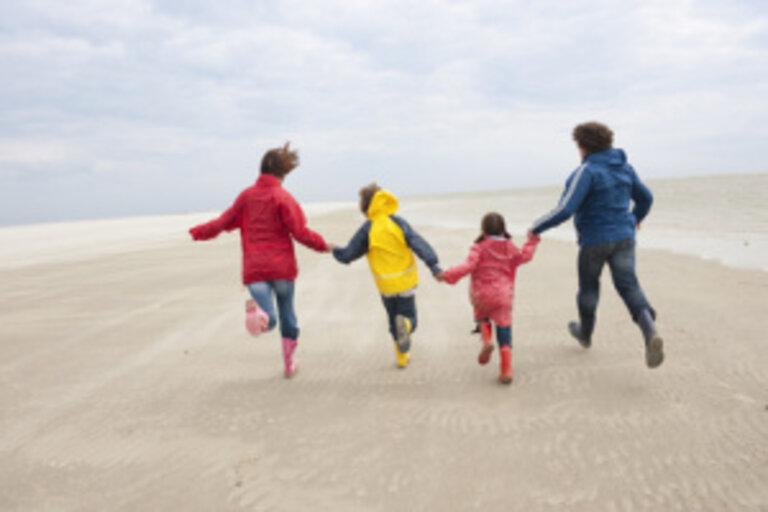 Deutschland, St. Peter-Ording, Nordsee, Familie hält zusammen und läuft am Strand