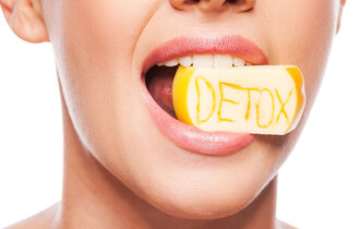 Frau beisst auf Stück Obst mit Schriftzug "Detox"