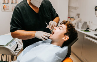 Ein Zahnarzt überprüft die Zähne eines Jungen