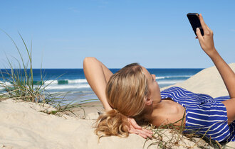 Frau mit Handy am Strand
