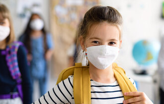 Kinder mit Atemschutzmaske im Klassenraum