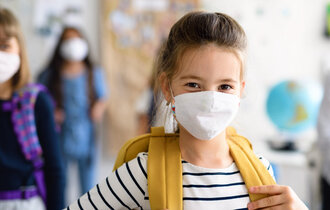 Kinder mit Atemschutzmaske im Klassenraum