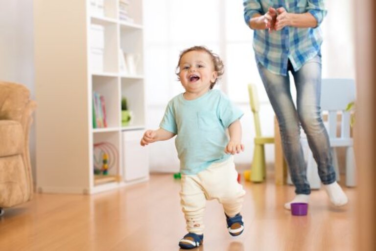 Baby boy running in living room with his mother