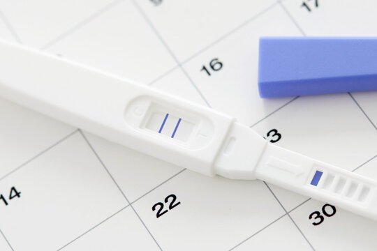  Ein Schwangerschaftstest mit zwei Streifen auf einem Kalender.