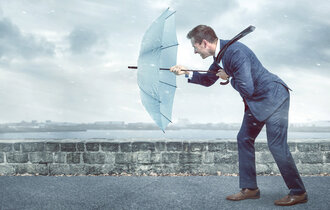 Businessman,With,An,Umbrella,Is,Facing,Strong,Headwind